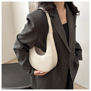 Detail view of cream white half-moon hobo bag worn by model in gray blazer