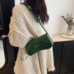 Deep green crocodile embossed shoulder bag with Miss mini logo and slim strap on model
