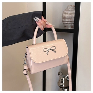 Detailed shot of a glossy pink square handbag featuring a silver metal bow buckle