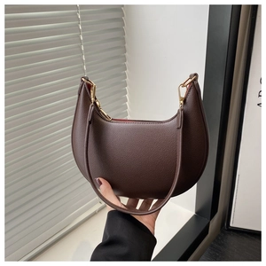 Detail der dunkelbraunen Halbmondtasche mit Narbenlederstruktur und goldenem Reißverschluss
