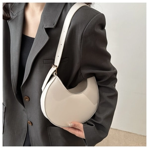 Detail of white crescent underarm bag with smooth finish and adjustable shoulder strap