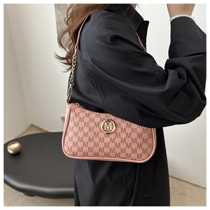 Detail of pink crescent bag with brown M-pattern, gold logo, and chain strap