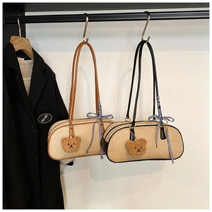 Detail of straw woven barrel bags with leather straps and cute plush bear charms
