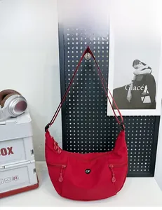 Détail du sac rouge en nylon avec doubles poches zippées et bandoulière réglable