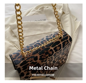 Detail of leopard print crossbody bag featuring thick gold chain and metallic buckle