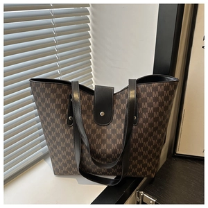 Macro view of monogram pattern tote bag with leather buckle detail and metallic hardware