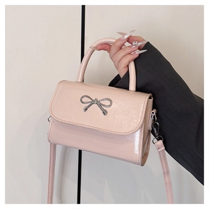 Detailed shot of pink patent leather square bag with silver bow accent and top handle
