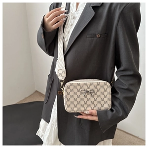 Close-up of vintage crossbody camera bag with brown M-pattern and wide woven strap
