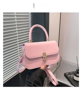 Close-up of pink PU leather shoulder bag with gold metal clasp and top handle details
