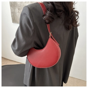 Close-up of red crescent shoulder bag worn with dark grey blazer for daily fashion