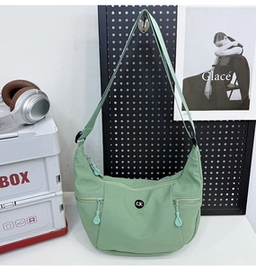 Détail du sac croissant en nylon vert clair avec bandoulière et logo métal CJC