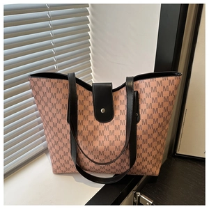 Close-up of monogram pattern tote bag with leather strap and magnetic snap closure