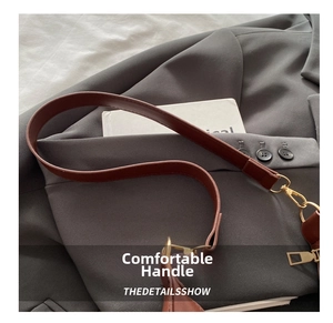 Detailaufnahme des dunkelbraunen Leder-Schultergurts mit goldener Metallschnalle für Taschen