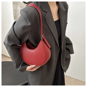 Red crescent shoulder bag shown on model with adjustable strap and gold hardware detail