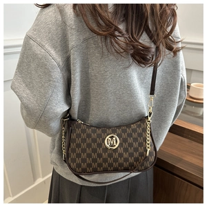 Detail of a dark brown crescent moon bag with M-pattern print and gold metal logo