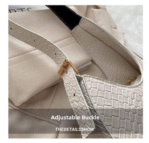 Detail of adjustable golden metal buckle and woven texture on a white crescent bag