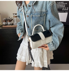 Mannequin portant un sac bandoulière bicolore noir et blanc avec pompon en corde