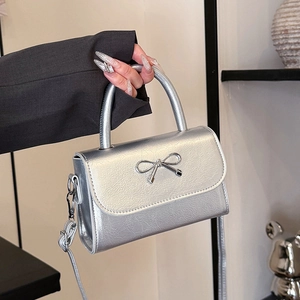 Chic silver crossbody handbag with pleated leather texture and a metallic bow detail