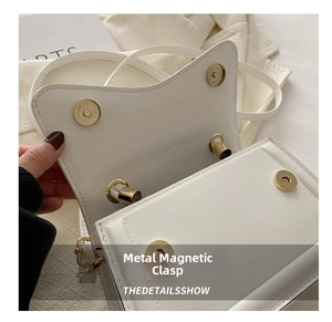 Detail of white faux leather bag showing gold magnetic closure and clean inner lining