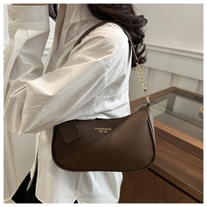 Détail du sac sous le bras en cuir marron foncé avec chaîne en métal doré et texture