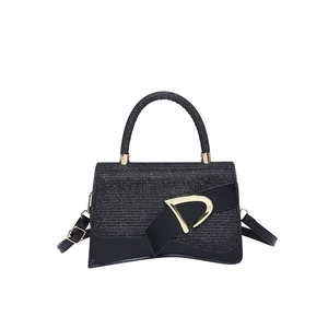 Elegant black glitter trapezoid handbag with gold D-buckle and signature curved base