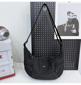 Détail du sac demi-lune en nylon noir avec bandoulière réglable et poches zippées à l'avant