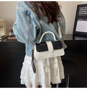 Détail du sac à bandoulière bicolore noir et blanc avec une écharpe décorative à rayures