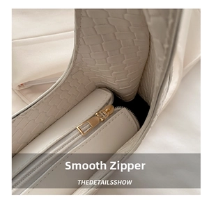 Detailed close-up of premium gold-toned smooth zipper and woven leather texture of the handbag