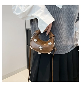 Close-up of brown crescent handbag with silver studs worn with a casual outfit