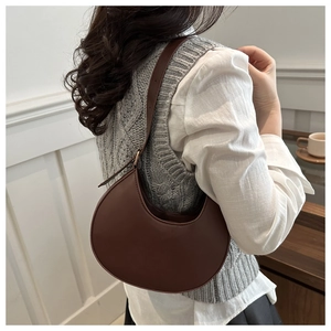 Close-up of brown crescent shoulder bag with golden metallic buckle adjustment