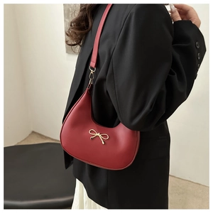 Nahaufnahme der goldenen Schleife am roten Leder-Halbmond-Schultertasche für Damen