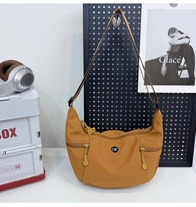 Détail du sac croissant en nylon gingembre avec trois poches zippées et logo circulaire