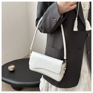 Detail of white wave-flap crossbody bag with smooth texture and sleek shoulder strap