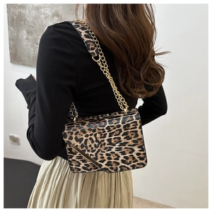 Detail of leopard print crossbody bag with gold chain strap and metallic lock buckle