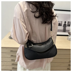 Shoulder bag detail featuring black litchi texture leather and gold chain decoration
