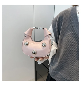 Detail of light pink crescent handbag with decorative silver metallic spheres