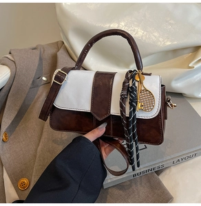 Détail d'un sac à main bicolore avec pendentifs de tennis et lanières en similicuir marron