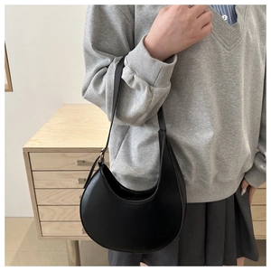 Detail of minimalist black crescent underarm bag in matte leather on a model