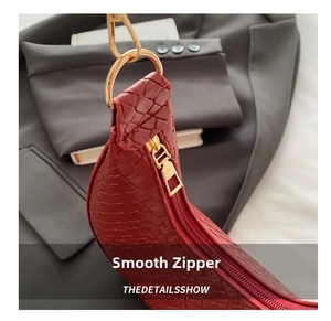 Close-up of wine red woven crescent bag with smooth golden zipper and metal D-ring buckle