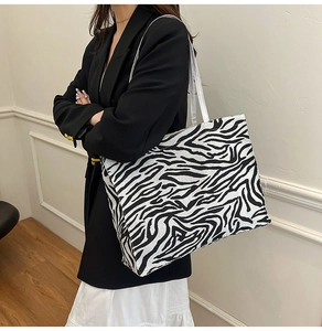 Chic zebra print canvas tote bag with white faux leather straps shown on a model