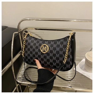 Close-up of black monogram underarm bag with gold metal M-logo and chain strap