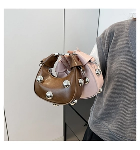 Detail showing two leather mini crescent bags in brown and pink with large silver studs