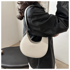 Detail of cream crescent shoulder bag with woven texture and adjustable metal buckle