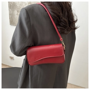 Deep red vintage underarm bag on shoulder of woman wearing a grey blazer jacket