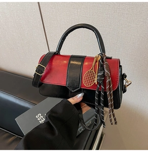 Détail du sac à main bicolore rouge et noir avec pendentif raquette de tennis