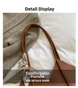 Close-up of brown leather tote bag handle featuring a geometric print silk scarf detail