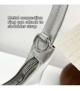 Detail of silver metallic handbag showing D-ring hardware and smooth zipper closure
