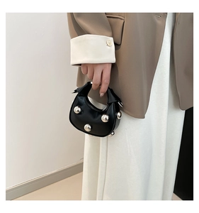 Close-up of mini black crescent bag featuring prominent silver metallic rivet studs