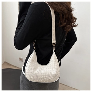 Detail of white crocodile embossed moon bag with metallic gold hardware and leather strap