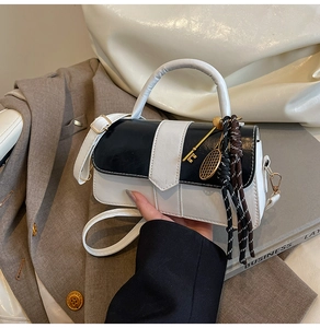 Détail du sac à main noir et blanc avec poignée ronde et pendentif raquette de tennis
